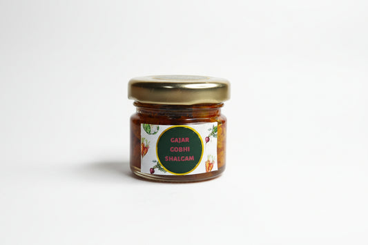 Small jar of gajar gobhi shalgam on a white surface with a blurred background